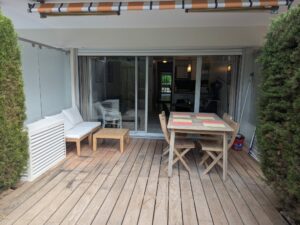 Terrasse en bois chaleureuse et élégante d’un appartement en location saisonnière, géré par la conciergerie Odyssée Riviera à Antibes & Juan-les-Pins